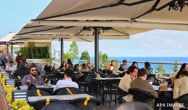 Turks, some wearing masks as a precaution against the spread of the coronavirus disease (COVID-19), sit in cafes, after the decision to open restaurants, cafes, cafeterias and public places in Istanbul, Turkey on June 3,...
