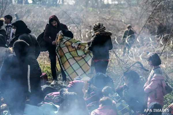 A picture taken on March 1, 2020. Refugees sit in a field near the Pazarkule gate in Edirne region, at the Turkish-Greek border. Migrants and refugees hoping to enter Greece from Turkey appeared to be fanning out across...