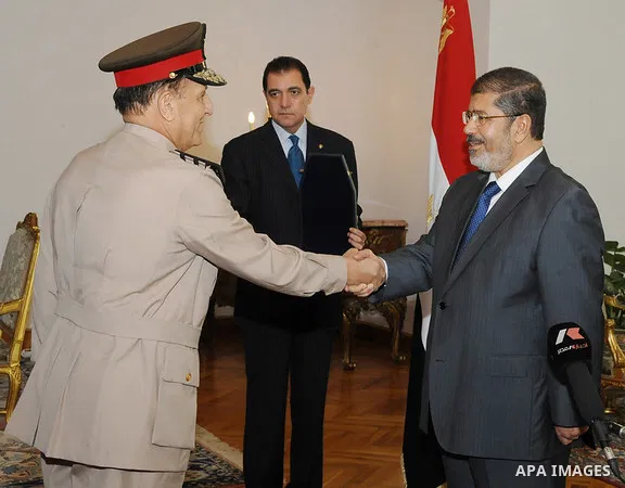 (FILES) This file photo taken on Aug. 14, 2012 shows Former Armed Forces Chief of Staff Sami Anan shakes hands with former Egyptian President Mohammed Morsi at the Presidential Palace in Cairo, Egypt. Sami Anan, former a...