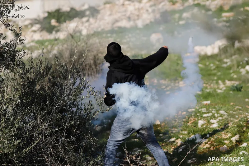 A Palestinian protester returns throwing a tear gas canister at the Israeli forces during clashes following a weekly demonstration against the expropriation of Palestinian land by Israel in the village of Kfar Qaddum, ne...