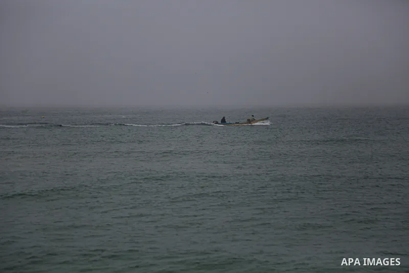 Palestinian fishermen work on their fishing boats during a heavy fog, in Gaza city, on January 5, 2021. Photo by Mahmoud Alhende