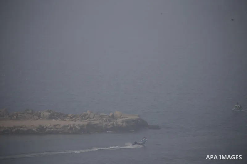 Palestinian fishermen work on their fishing boats during a heavy fog, in Gaza city, on January 10, 2021. Photo by Osama Baba