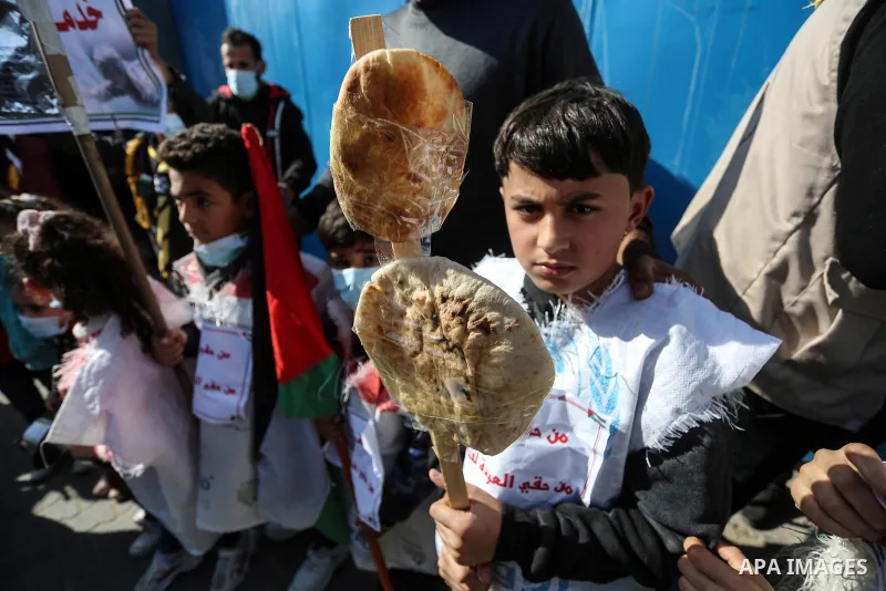 Palestinian children hold banners with Arabic slogans like "We are all hungre", take part in a protest against the reduction of the food basket provided by the United Nations Relief and Works Agency for Palestine Refugee...