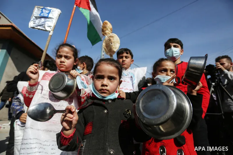 Palestinian children hold banners with Arabic slogans like "We are all hungre", take part in a protest against the reduction of the food basket provided by the United Nations Relief and Works Agency for Palestine Refugee...