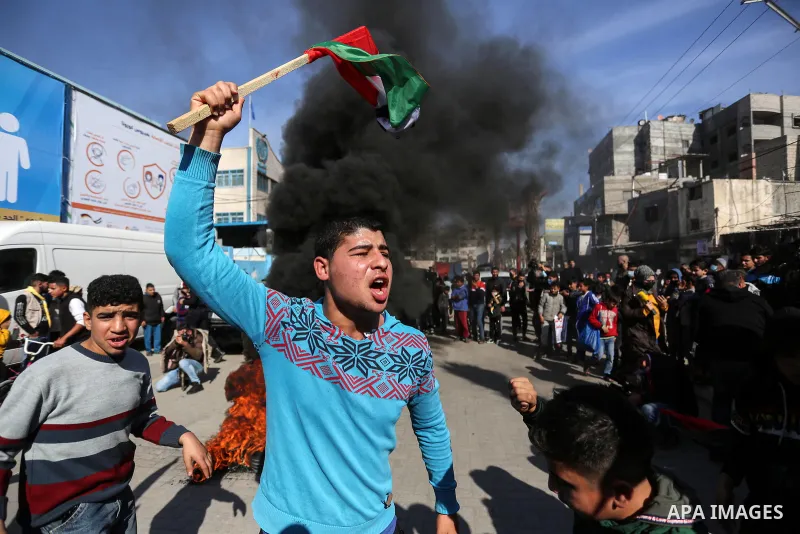 A Palestinian protester wave a national flag, shouts slogans during a protest against the reduction of the food basket provided by the United Nations Relief and Works Agency for Palestine Refugees (UNRWA), in front of th...