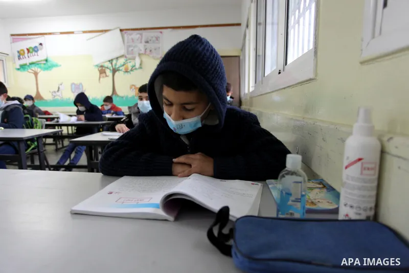 Palestinian students wear protective face masks, listen to their teacher as schools gradually reopen amid the coronavirus disease (COVID-19) outbreak, at their school in Gaza city, on January 13, 2021. In a written state...