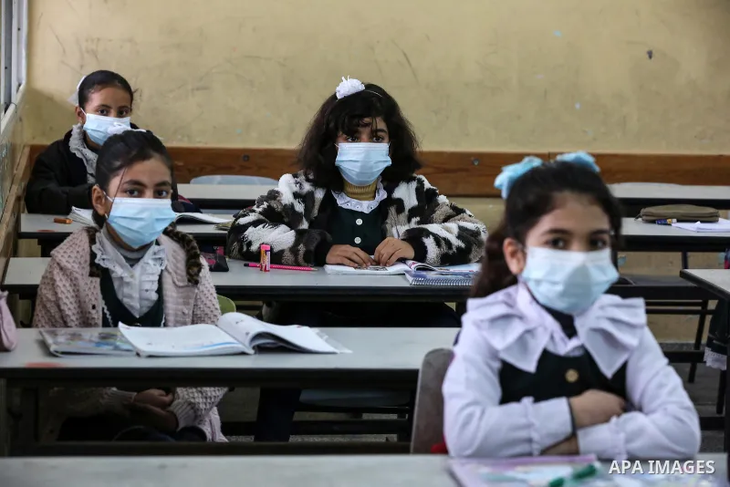 Palestinian students wear protective face masks, listen to their teacher as schools gradually reopen amid the coronavirus disease (COVID-19) outbreak, at their school in Khan Younis in the southern of Gaza strip, on Janu...