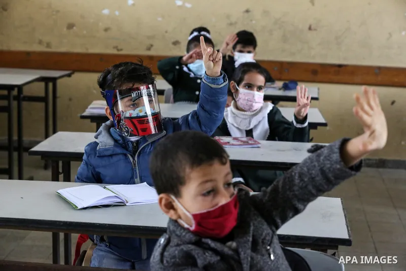 Palestinian students wear protective face masks, listen to their teacher as schools gradually reopen amid the coronavirus disease (COVID-19) outbreak, at their school in Khan Younis in the southern of Gaza strip, on Janu...
