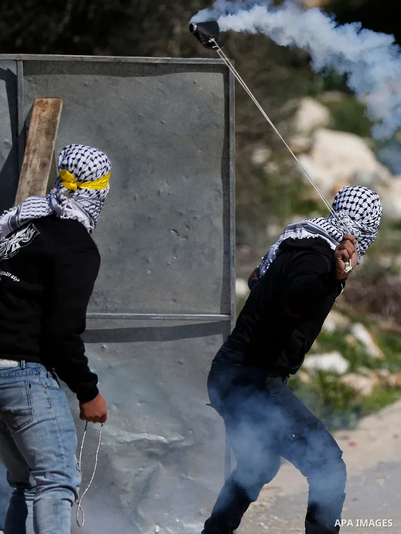 A Palestinian protester returns throwing a tear gas canister at the Israeli forces during clashes following a weekly demonstration against the expropriation of Palestinian land by Israel in the village of Kfar Qaddum, ne...