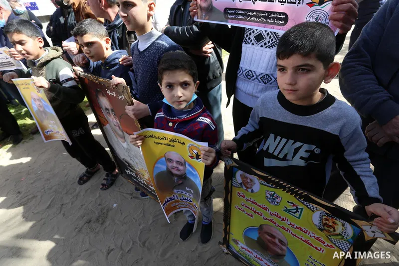 Palestinians hold posters of Mohammad El Halabi, World Vision's manager of operations in Gaza who was accused by Israel of funnelling millions of dollars in aid money to Hamas, during a protest in solidarity with El Hala...
