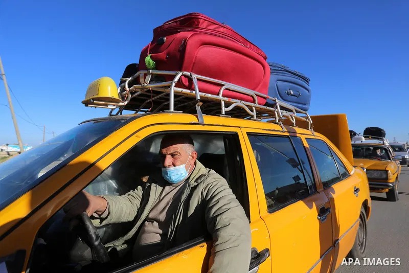 Palestinians wearing protective masks amid the COVID-19 pandemic, as they wait for travel permits to cross into Egypt through the Rafah border crossing, in Rafah in the southern of Gaza Strip, on February 1, 2021, after...