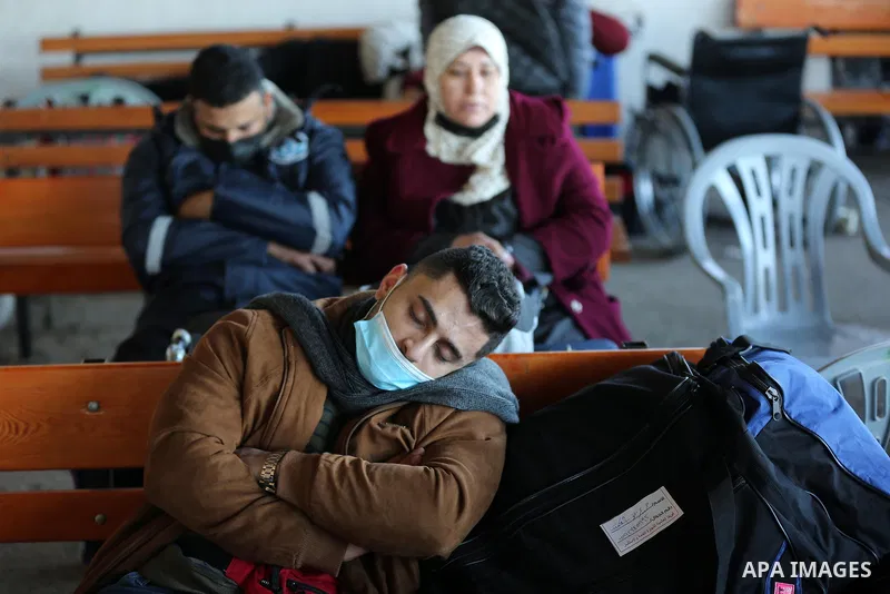 Palestinians wearing protective masks amid the COVID-19 pandemic, as they wait for travel permits to cross into Egypt through the Rafah border crossing, in Rafah in the southern of Gaza Strip, on February 1, 2021, after...