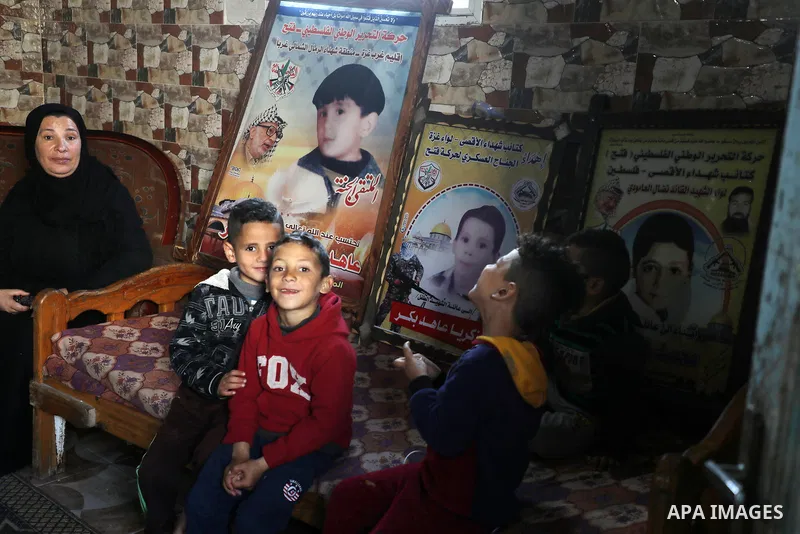 Members of the Bakr family gather in their house in al-Shati refugee camp in Gaza City on February 7, 2021, surrounded by posters in memory of four children from their extended family who were killed during the 2014 Isra...