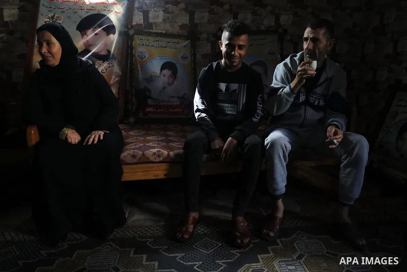 Members of the Bakr family gather in their house in al-Shati refugee camp in Gaza City on February 7, 2021, surrounded by posters in memory of four children from their extended family who were killed during the 2014 Isra...
