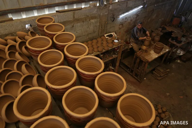 Palestinian Sayed Atallah, 40, works at a pottery workshop with thier sons in Deir al-Balah in the central Gaza Strip, on February 14, 2021. Pottery is the process and the products of forming vessels and other objects wi...