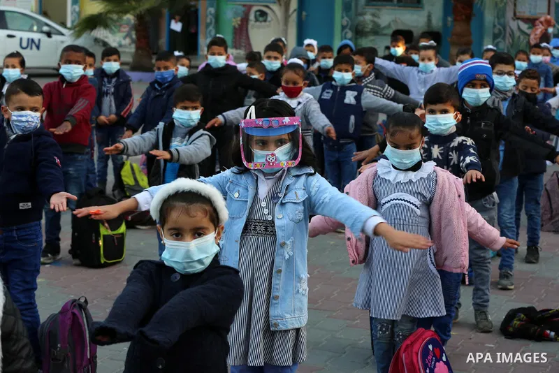 Palestinian students wearing protective face masks, as schools gradually reopen amid the coronavirus disease (COVID-19) outbreak, at their school run by the United Nations Relief and Works Agency (UNRWA) in Deir al-Balah...