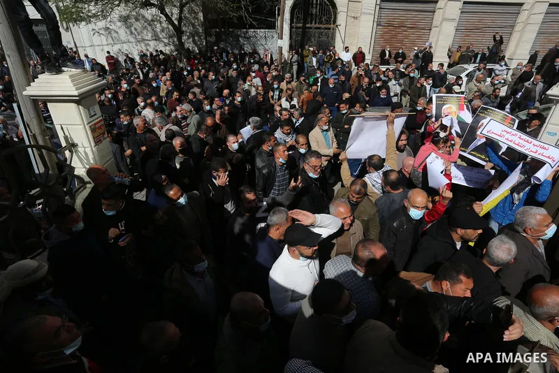 Palestinian military retirees, hold pictures of President Mahmoud Abbas during a protest to demand the cancellation of the Mandatory retirement law, in Gaza city, on February 14, 2021. Mandatory retirement also known as...