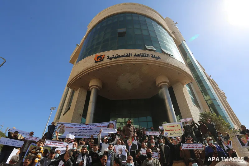 Palestinian military retirees, hold pictures of President Mahmoud Abbas during a protest to demand the cancellation of the Mandatory retirement law, in Gaza city, on February 14, 2021. Mandatory retirement also known as...