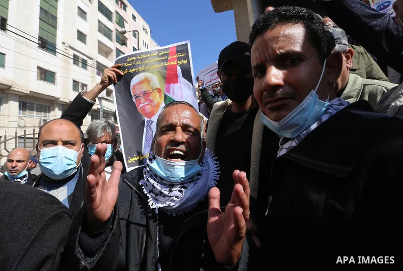 Palestinian military retirees, hold pictures of President Mahmoud Abbas during a protest to demand the cancellation of the Mandatory retirement law, in Gaza city, on February 14, 2021. Mandatory retirement also known as...