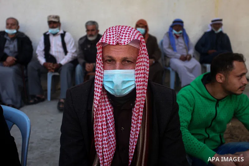 Palestinian families of martyrs and woundeds wearing protective face masks, as they take part in a protest to demand their rights and salaries, in front of the headquarters of the Martyrs and Wounded Foundation, in Gaza...