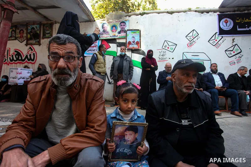 Palestinian families of martyrs and woundeds wearing protective face masks, as they take part in a protest to demand their rights and salaries, in front of the headquarters of the Martyrs and Wounded Foundation, in Gaza...