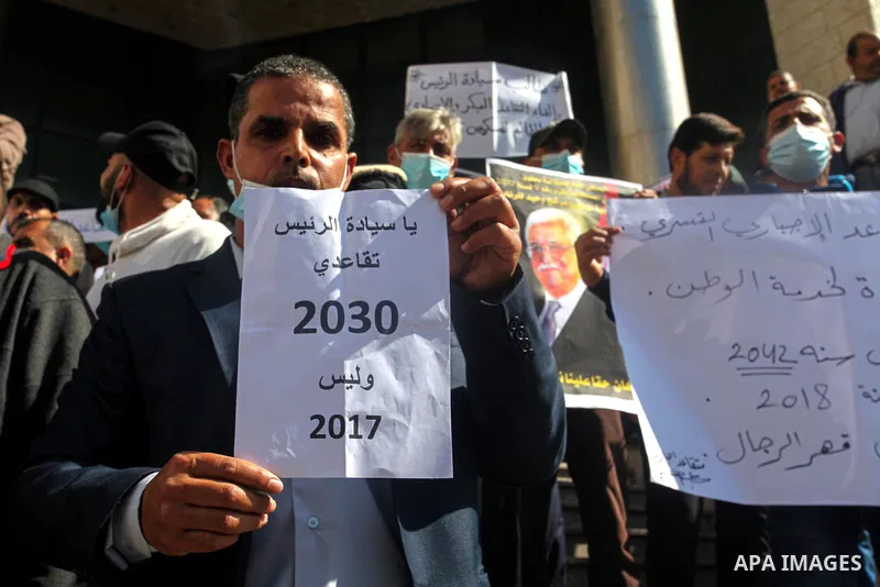 Palestinian military retirees, hold pictures of President Mahmoud Abbas during a protest to demand the cancellation of the Mandatory retirement law, in Gaza city, on February 14, 2021. Mandatory retirement also known as...