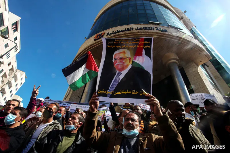 Palestinian military retirees, hold pictures of President Mahmoud Abbas during a protest to demand the cancellation of the Mandatory retirement law, in Gaza city, on February 14, 2021. Mandatory retirement also known as...