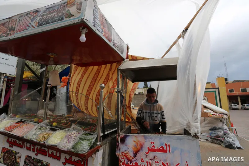 A Palestinian vendor sells fast food during a stormy day, in Dair Al Balah in the central of Gaza Strip, on February 16, 2021. Photo by Ashraf Amra