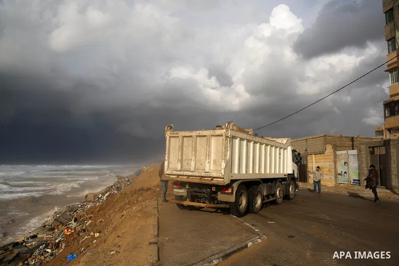 Palestinian workers lay sand to protect homes overlooking the coast in al-Shati refugee camp in Gaza City on February 17, 2021. The cloudy, stormy and very cold conditions are expected to continue on Thursday. Scattered...
