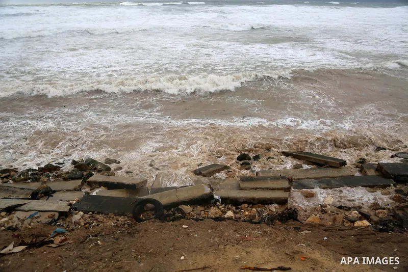 Palestinian workers lay sand to protect homes overlooking the coast in al-Shati refugee camp in Gaza City on February 17, 2021. The cloudy, stormy and very cold conditions are expected to continue on Thursday. Scattered...