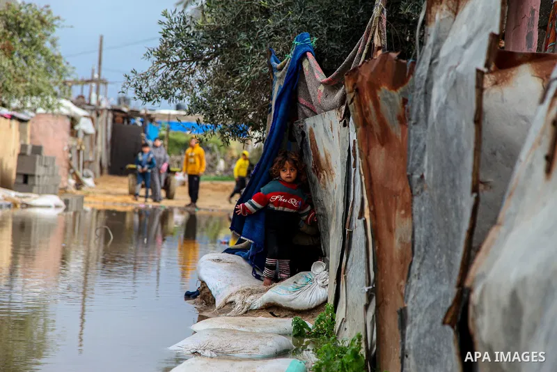 Palestinians walk in a street flooded by rain water during a stormy day, in Beit Lahia in the northern Gaza Strip on February 18, 2021. In the Gaza Strip, several people were hurt and damage caused to homes in various ar...
