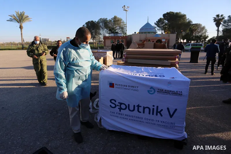 Health workers stand stand next to boxes of Russian-made Sputnik V vaccine doses from the United Arab Emirates, upon the arrival of a truck load in the Gaza Strip via the Rafah crossing with Egypt, on February 21, 2021....