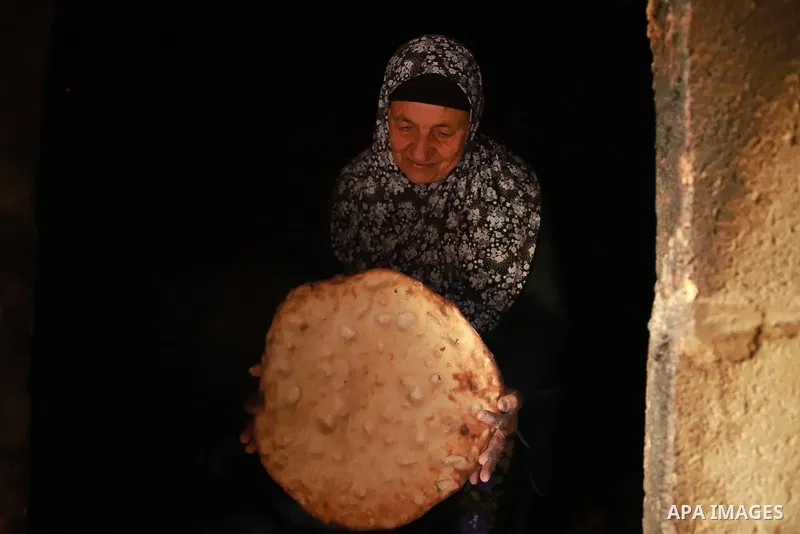 Two elderly Palestinian, Jazia Abu Kabbash, 80, and Ghazlan Abu Karsh, 70, prepare the traditional bread "Taboon", in Al-Samou town southern of the West Bank city of Hebron, on February 23, 2021. Taboon bread is Levantin...