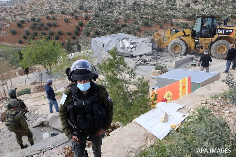 Israeli forces stand guard as Israeli machinery demolish a Palestinian house located within the area C (where Israel retains control, including over planning and construction) in a village south of Yatta in the southern...