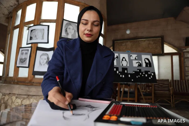 Palestinian artist Zeina Al-Shurafa paints a painting depicting a woman's face, for solidarity with battered woman, in her home in Gaza City on March 10, 2021. Palestinian female victims of domestic violence have little...