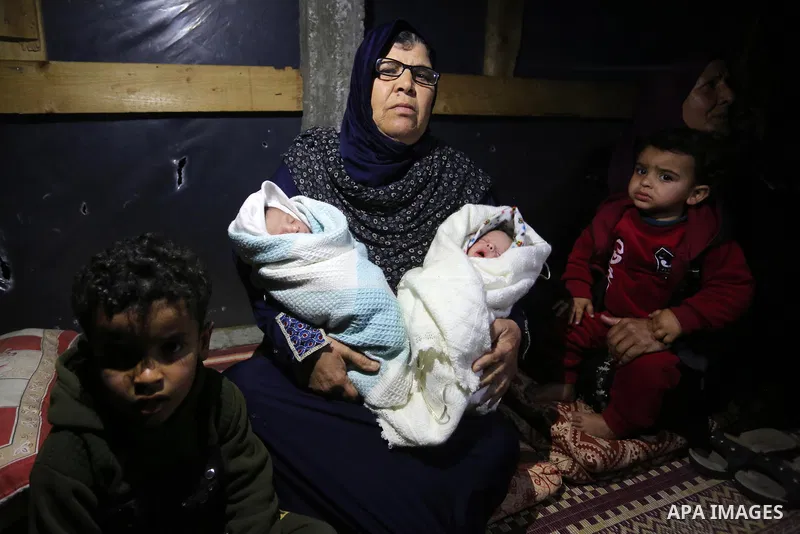 Palestinian Umm Basim al-Lahham, holds her grandchildren and sits with them in her house after her sons were killed when their boat exploded off Gaza's coast in the Mediterranean Sea, in Khan Yunis in the southern Gaza S...