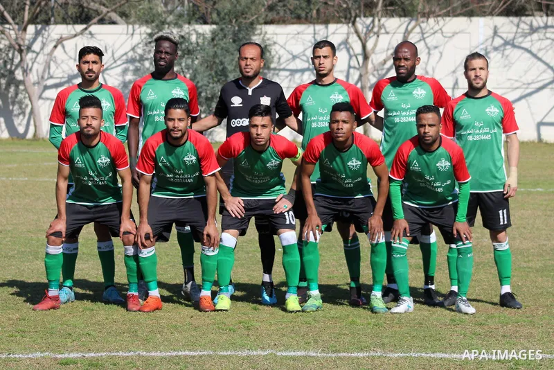Palestinian football players of Shabab Jabalia (blue) and Khadamat Rafah club (green) compete during match premier League in Beit Lahia Stadium, in Beit Lahia in the northern Gaza Strip on March 28, 2021. Photo by Mariha...