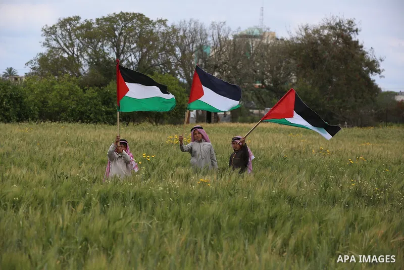 Palestinians carry the Palestinian flag near the border with Israel, in Khan Younis in the southern of Gaza Strip, on March 30, 2021. Palestinians every year mark Land Day on March 30 commemorating the six Palestinians s...