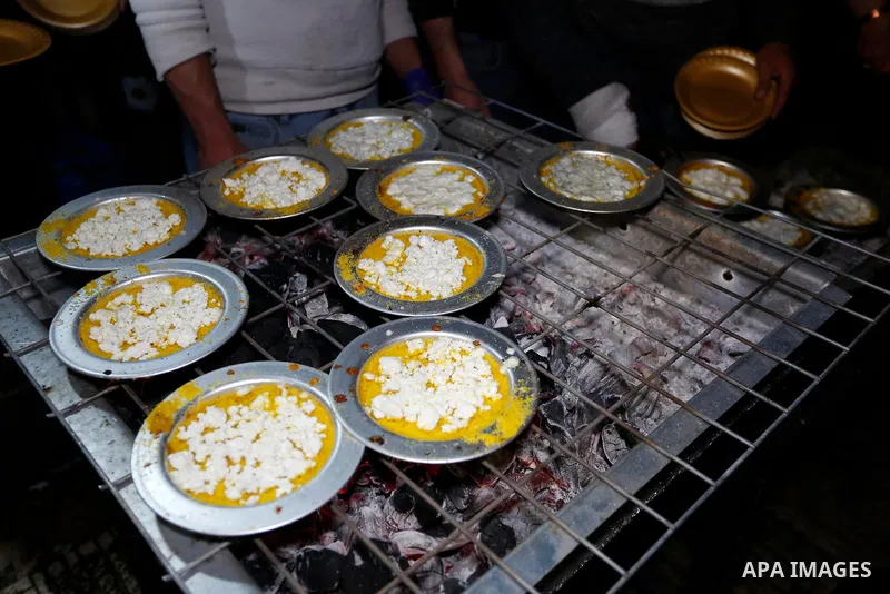 Palestinian men prepare a traditional Konafa "Nablusia", on a street, amid the coronavirus disease (COVID-19) outbreak, in the West Bank city of Nablus, on March 31, 2021. Kanafeh is a traditional Middle Eastern dessert...