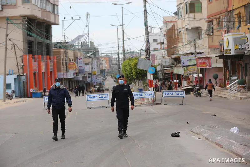 Palestinian policemen wear face masks, guard a barrier blocking a road, during a closure amid the spread of the Coronavirus COVID-19, in Deir El-Balah, in the center of the Gaza Strip, on April 2, 2021. after the Ministr...