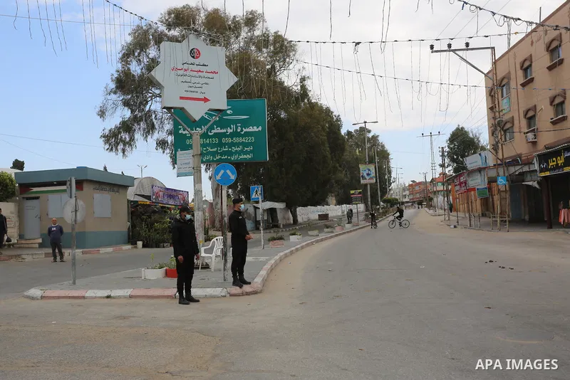 Palestinian policemen wear face masks, guard a barrier blocking a road, during a closure amid the spread of the Coronavirus COVID-19, in Deir El-Balah, in the center of the Gaza Strip, on April 2, 2021. after the Ministr...