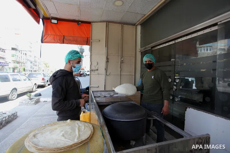 Palestinian men wear protective face masks, as they bake a traditional bread, during a lockdown following the outbreak of the coronavirus disease (COVID-19), in Gaza city, on April 8, 2021. Hospitals in the Palestinian T...