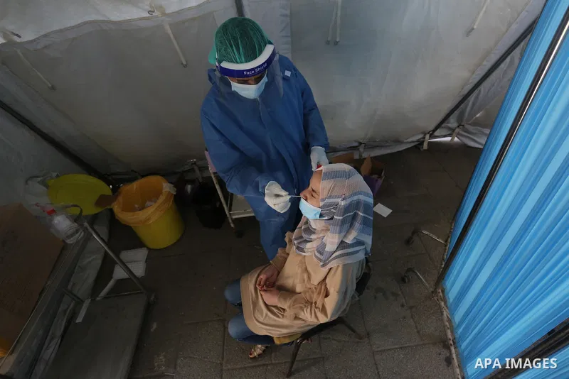 A Palestinian health worker collects a swab sample from a person for Covid-19 test in Deir al-Balah in the central Gaza Strip, on April 8, 2021. Hospitals in the Palestinian Territories of the West Bank and Gaza are bein...