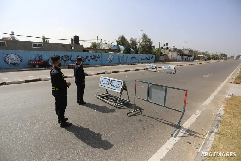 Palestinian policemen wear face masks, guard a barrier blocking a road, in Deir al-Balah in the central Gaza Strip, on April 8, 2021. Hospitals in the Palestinian Territories of the West Bank and Gaza are being overwhelm...