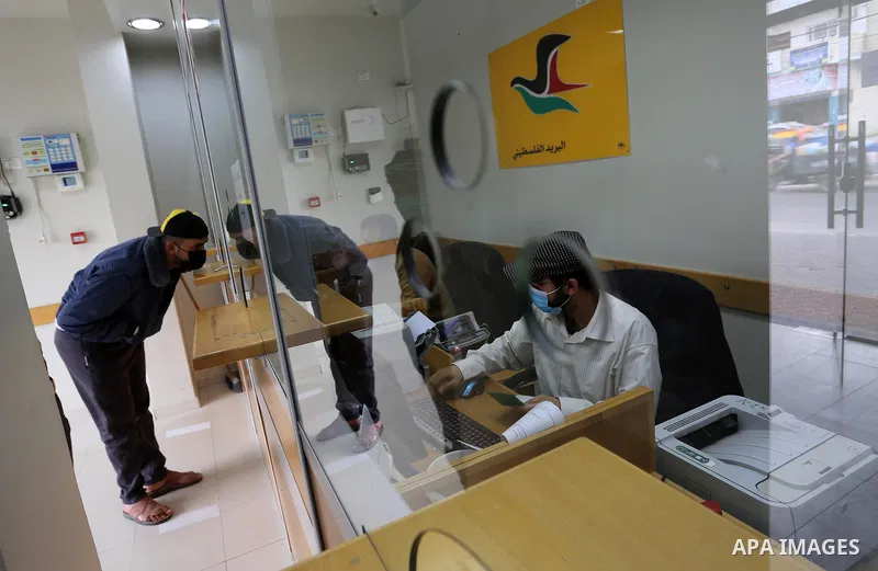 Palestinians wear protective face masks, as they wait to receive their financial aid, amid the coronavirus disease (COVID-19) outbreak, at the Post Office, in Dair Al Balah in the central of Gaza Strip, on April 10, 2021...