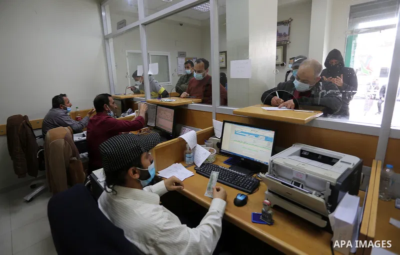 Palestinians wear protective face masks, as they wait to receive their financial aid, amid the coronavirus disease (COVID-19) outbreak, at the Post Office, in Dair Al Balah in the central of Gaza Strip, on April 10, 2021...