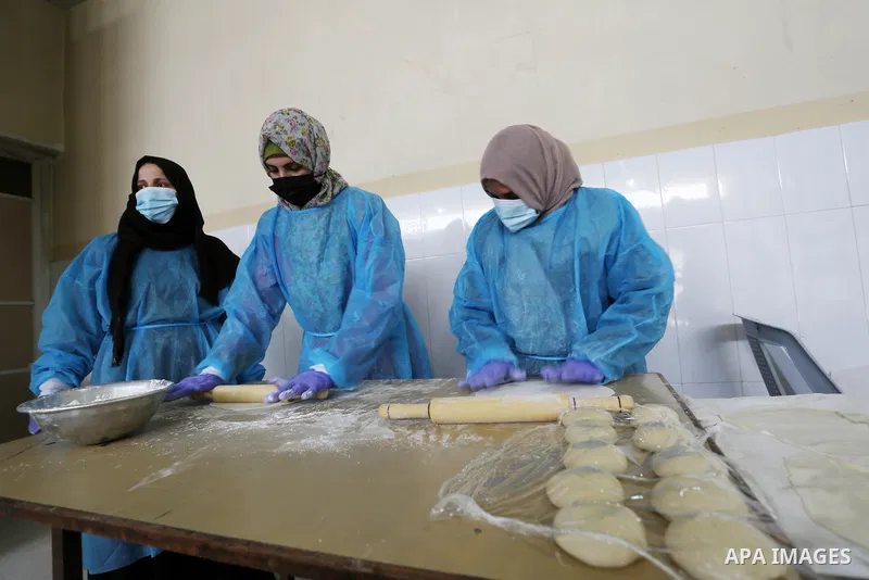 Palestinian women wear protective and maskes prepare traditional food of Couscous "Maftoul", samosa and Kubba in Khan Younis in the southern Gaza Strip, on April 11, 2021 to sell it to customers a head of Islamic holy mo...