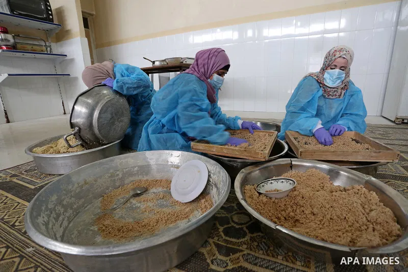 Palestinian women wear protective and maskes prepare traditional food of Couscous "Maftoul", samosa and Kubba in Khan Younis in the southern Gaza Strip, on April 11, 2021 to sell it to customers a head of Islamic holy mo...