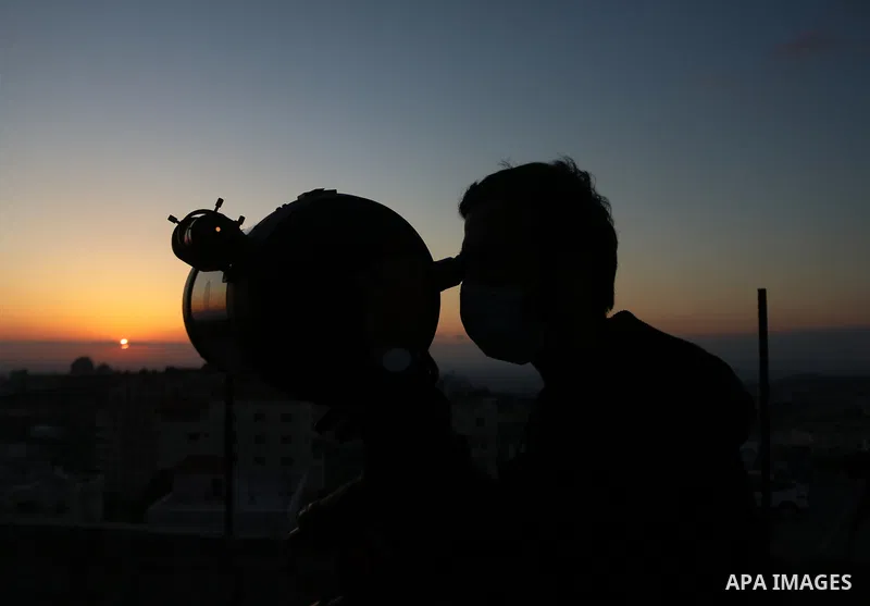 Palestinians uses a telescope to scan the horizon for a crescent moon that will determine the beginning of the holy fasting month of Ramadan, in the West Bank city of Hebron on April 12, 2021. The Grand Mufti of Jerusale...