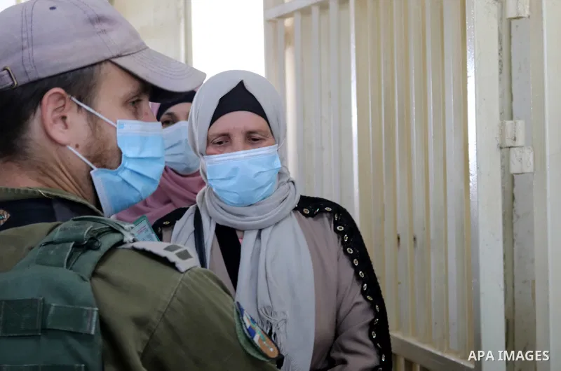 Palestinians entering Jerusalem to attend the first Friday prayers of the Muslim fasting month of Ramadan at the Al-Aqsa Mosque, show their covid-19 vaccination certificates to Israeli security forces at a checkpoint nea...